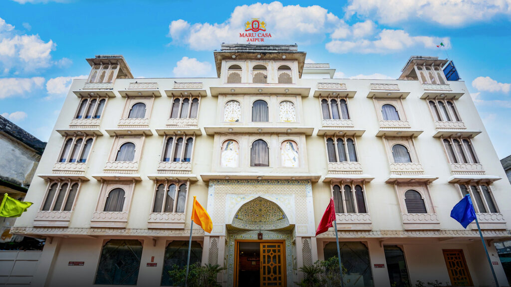 Maru Casa Jaipur hotel exterior with elegant heritage architecture under a bright blue sky.